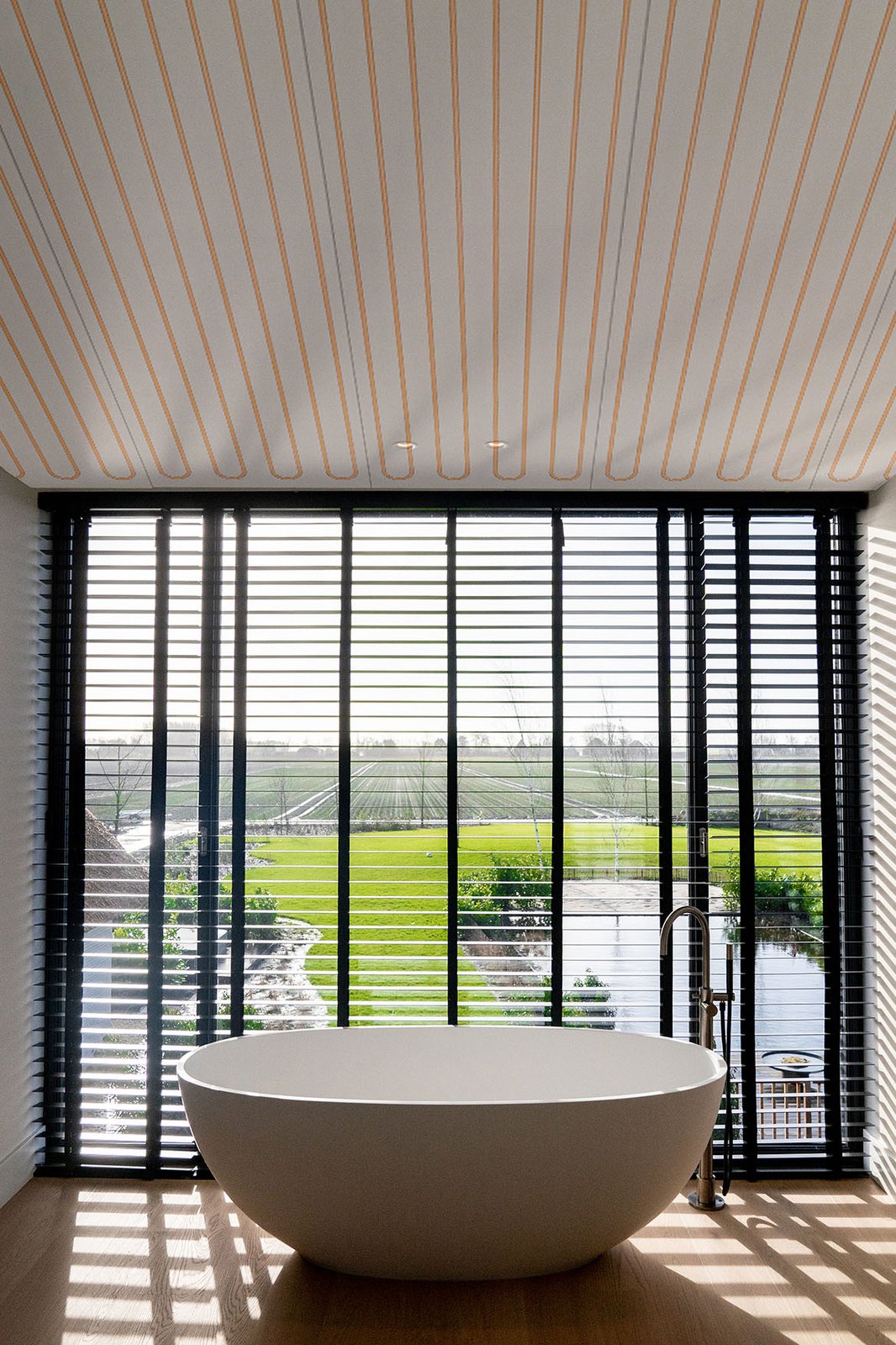 Badkamer met vrijstaand bad voor een raam, met klimaatplafond