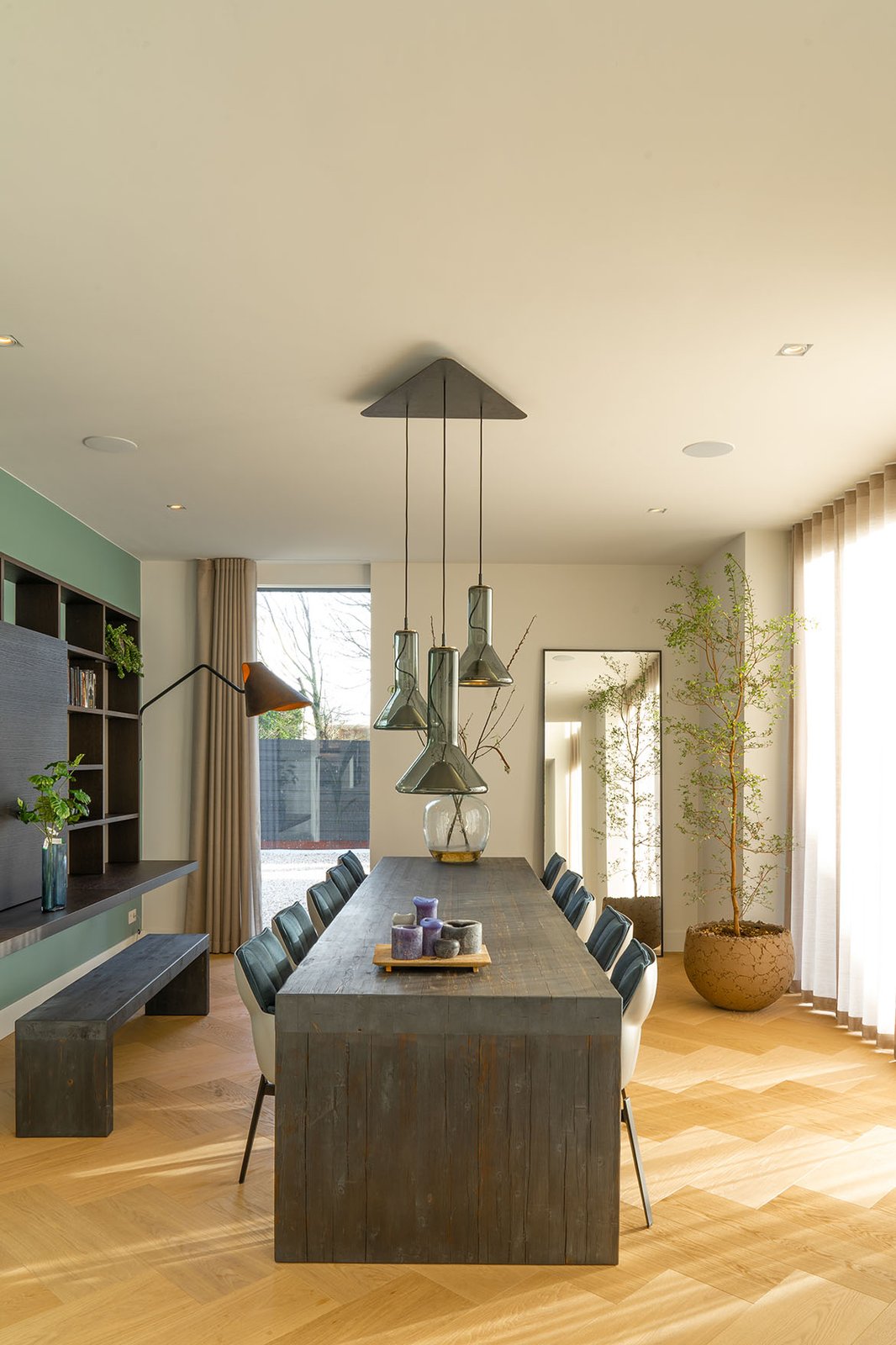 Eetkamer met lange tafel en hanglampen onder het klimaatplafond