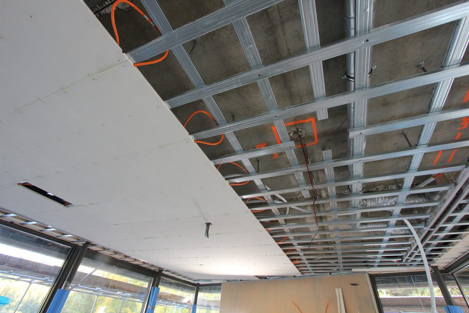 Metal stud regelwerk aan het plafond met de eerste klimaatplafondplaten en de aansluitleidingen