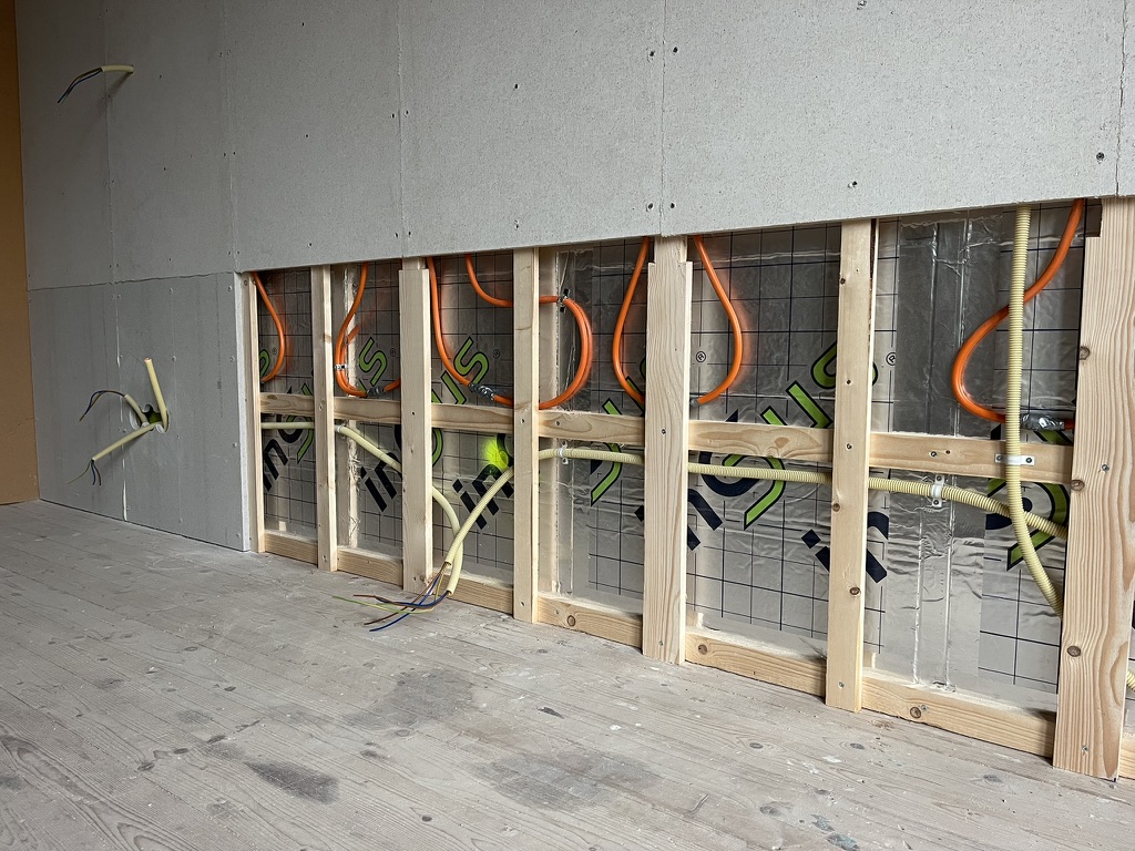 Onderkant van een voorzetwand met moduleplaten, met de buisaansluitingen tussen het regelwerk